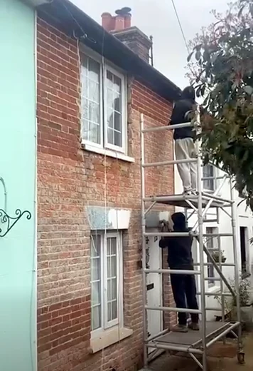 Scaffold tower against a brick cottage wall